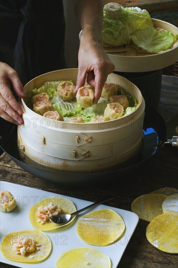 Person putting Asian dumplings in steamer with cabbage