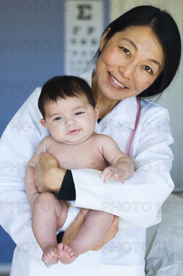 Doctor holding baby in office