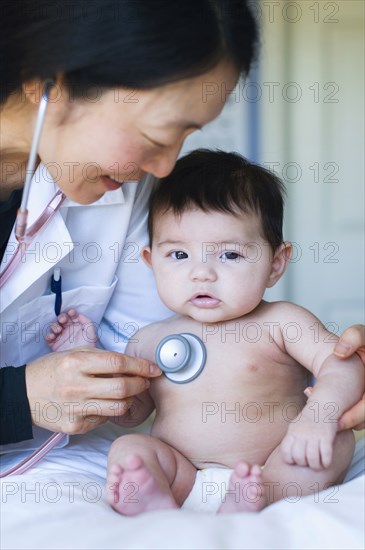 Doctor listening to baby's heartbeat in office