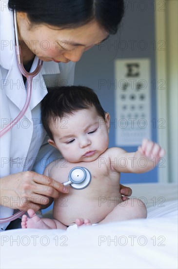 Doctor listening to baby's heartbeat in office