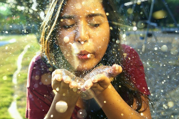 Hispanic teenage girl playing with glitter outdoors