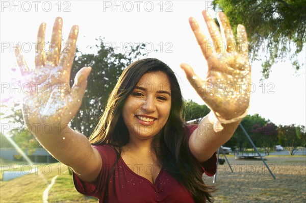 Hispanic teenage girl playing with glitter outdoors