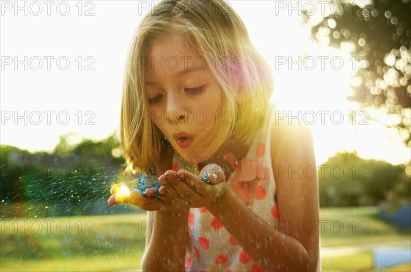 Hispanic girl playing with glitter outdoors