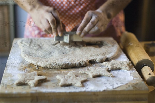 Mixed race woman cutting cookie dough in kitchen