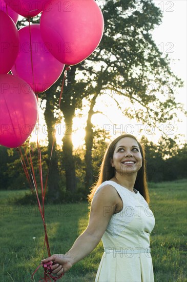 Mixed race woman with pink balloons in park