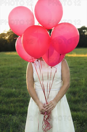 Mixed race woman with pink balloons in park