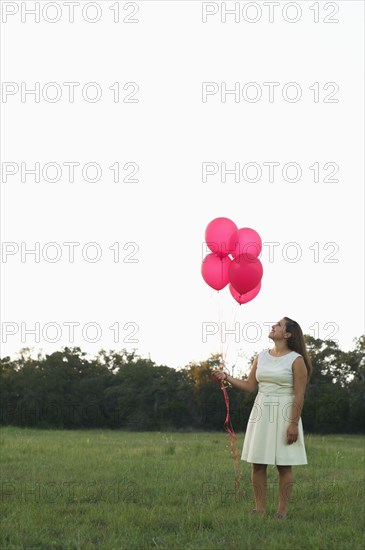 Mixed race woman with pink balloons in park