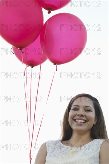 Mixed race woman with pink balloons