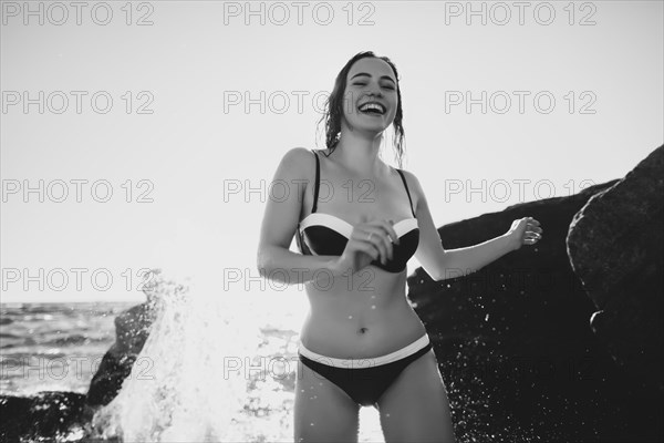 Smiling Caucasian woman standing on beach in bikini