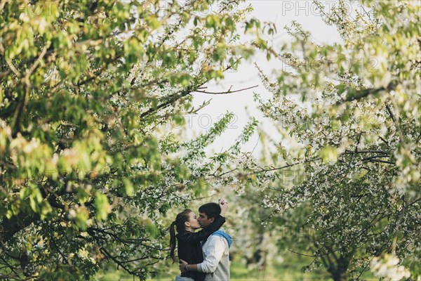 Caucasian couple kissing near trees