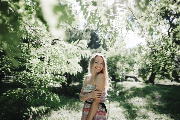 Caucasian woman standing near green trees