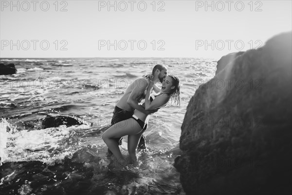 Caucasian couple laughing in ocean waves