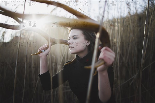 Caucasian woman holding antlers around head