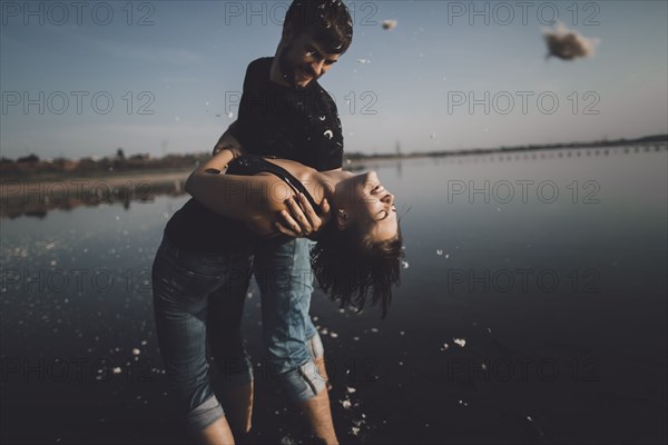 Caucasian man dipping woman at lake