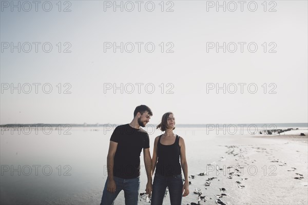 Caucasian couple holding hands on beach