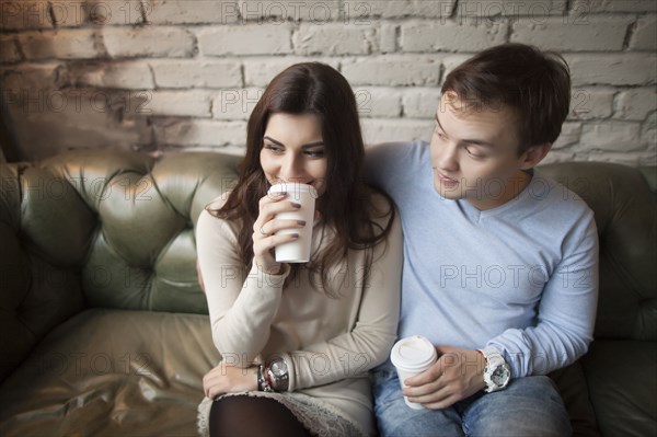 Caucasian couple drinking coffee on sofa