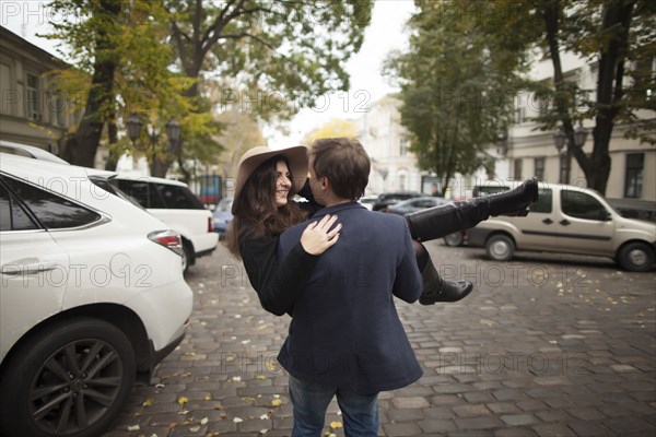 Caucasian man carrying woman on cobblestone street