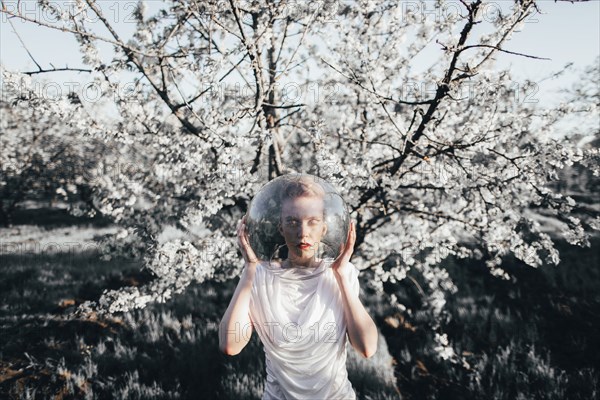 Caucasian teenage girl wearing bowl on head near flowering tree