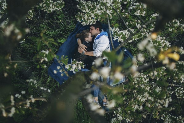 Caucasian couple laying in grass under flowering trees