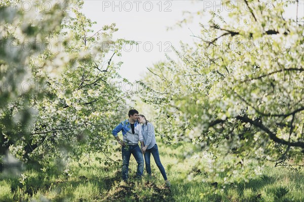 Caucasian couple holding hands under flowering trees