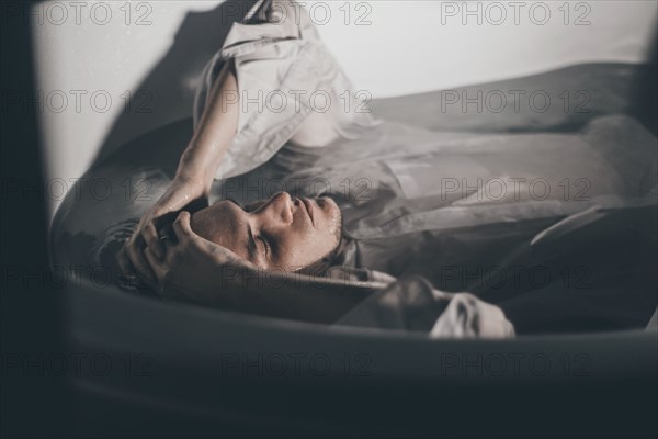 Caucasian man wearing shirt laying underwater in bathtub