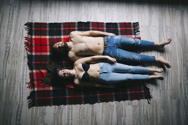 Caucasian couple laying flat on plaid blanket