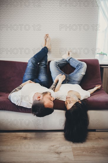 Caucasian couple laying upside-down on sofa