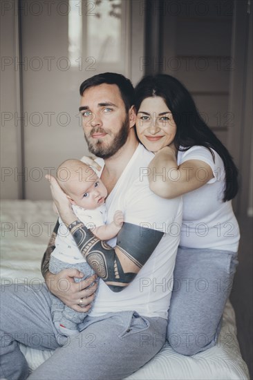 Portrait of Caucasian mother and father on bed with baby son