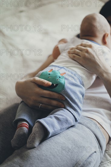 Caucasian mother laying on bed holding baby son