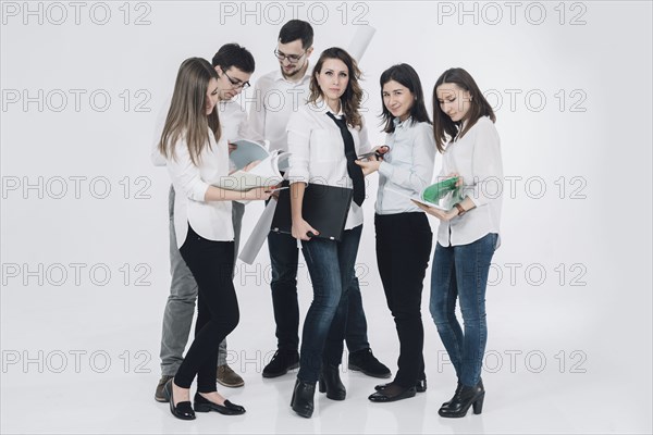 Caucasian woman holding laptop near co-workers reading paperwork