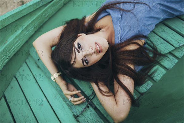 Caucasian woman laying on green boardwalk