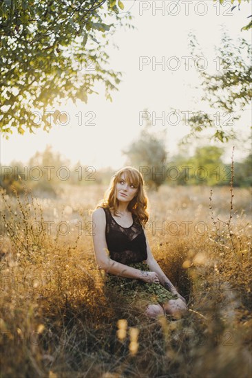 Pensive Caucasian woman kneeling in woods