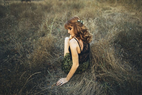 Pensive Caucasian woman sitting on grass