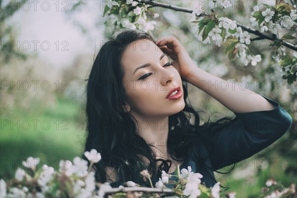 Caucasian woman with hand and hair near flowering tree