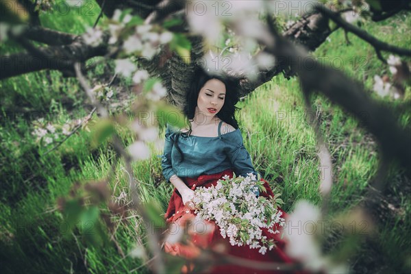 Caucasian woman leaning on tree holding flowers