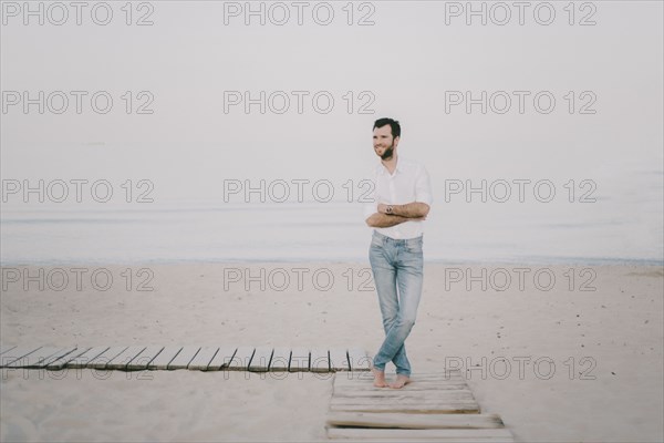 Caucasian man standing on boardwalk at beach