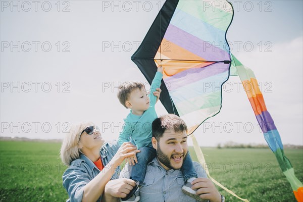 Caucasian boy flying kite with father and grandmother