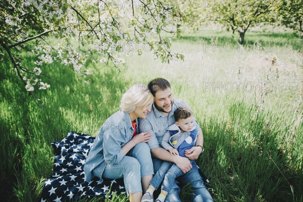 Caucasian multi-generation family sitting on blanket in grass