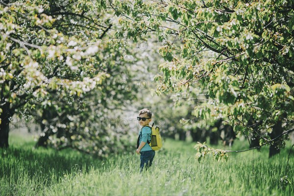 Caucasian boy wearing sunglasses and backpack in grass