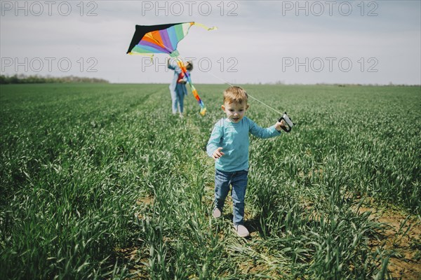 Caucasian boy and grandmother flying kite in field