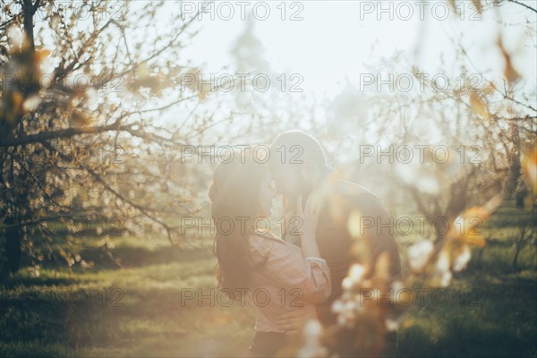 Caucasian couple rubbing noses near trees