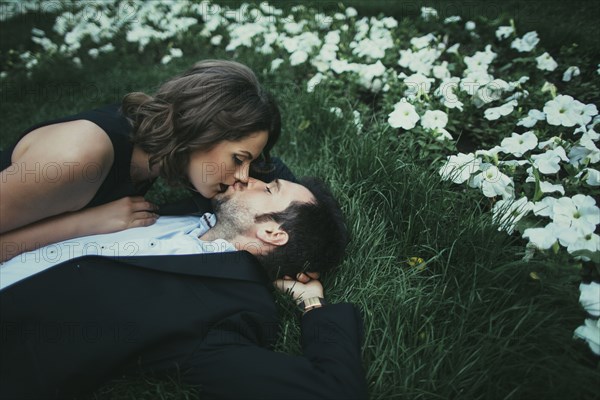 Caucasian couple laying in grass kissing