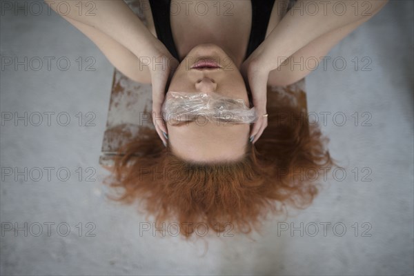 Caucasian woman covering eyes with plastic