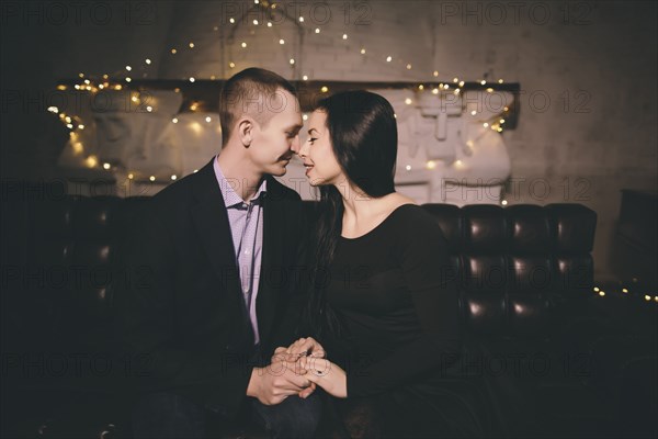 Caucasian couple sitting on sofa rubbing noses