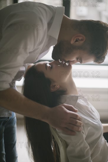 Caucasian man kissing woman in chair