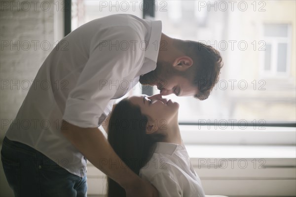 Caucasian man kissing woman in chair