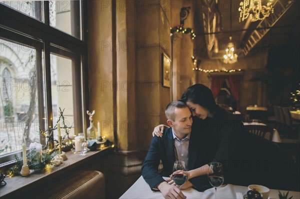 Caucasian couple drinking wine and hugging in restaurant