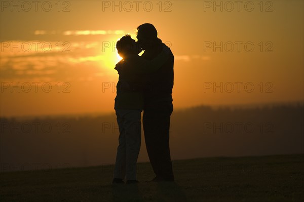 Hispanic couple kissing outdoors at sunset