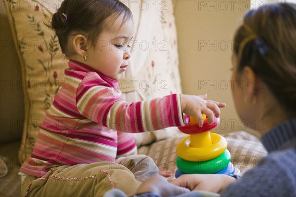 Hispanic mother watching daughter stack plastic rings