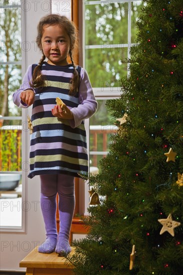 Mixed race girl decorating Christmas tree